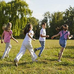 Eine Gruppe Kinder spielt auf einer Wiese.